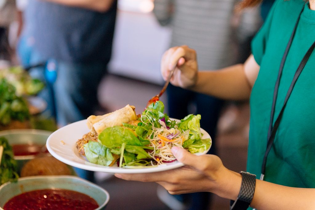 An employee serving themselves a plate of salad