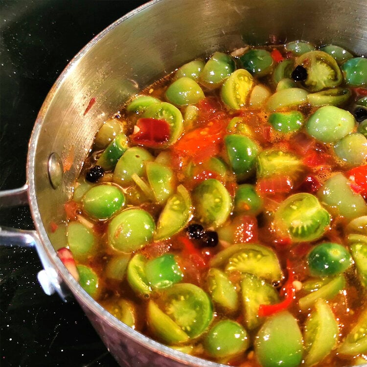 green tomatoes chopped and cooking in a pot to make chutney.