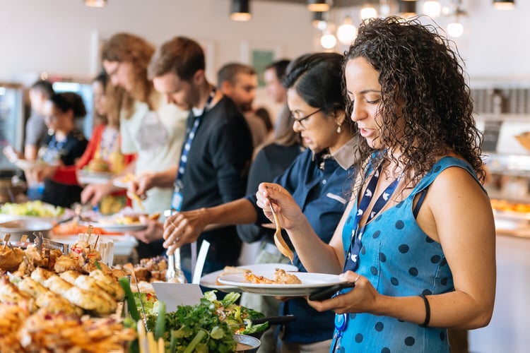Image of employees plating up with buffet lunch offered by contract caterer Fooditude. 