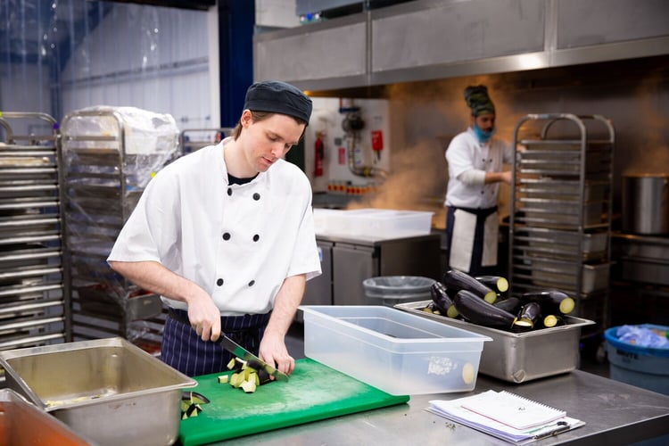 Chef in the fooditude kitchen chopping up vegetables.