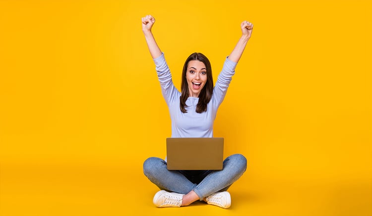 An employee sat cross-legged with hands-up in the air celebrating.