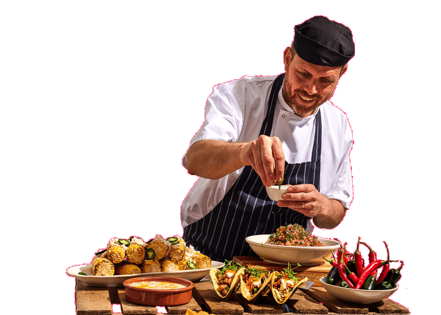 Chef sprinkling herbs on a plate of food