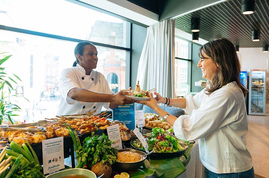 A female chef handing a woman a plate of food 