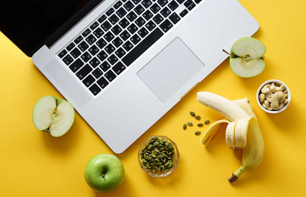 A yellow table with a laptop and fruit