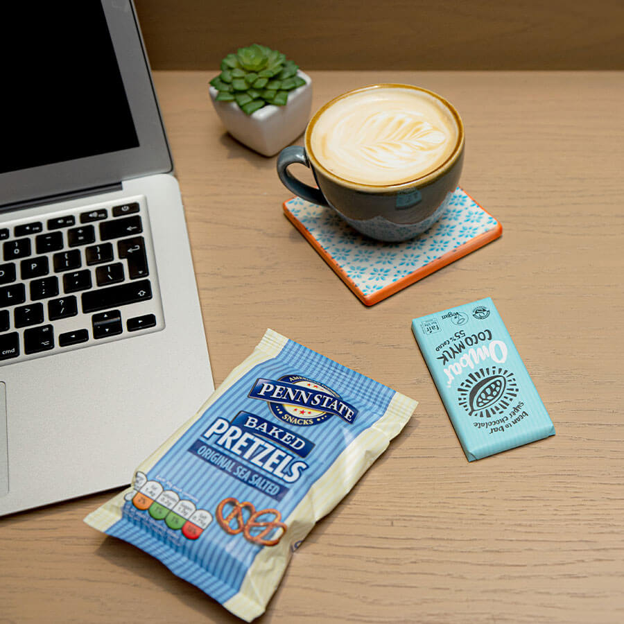 A table with a laptop, coffee and snacks